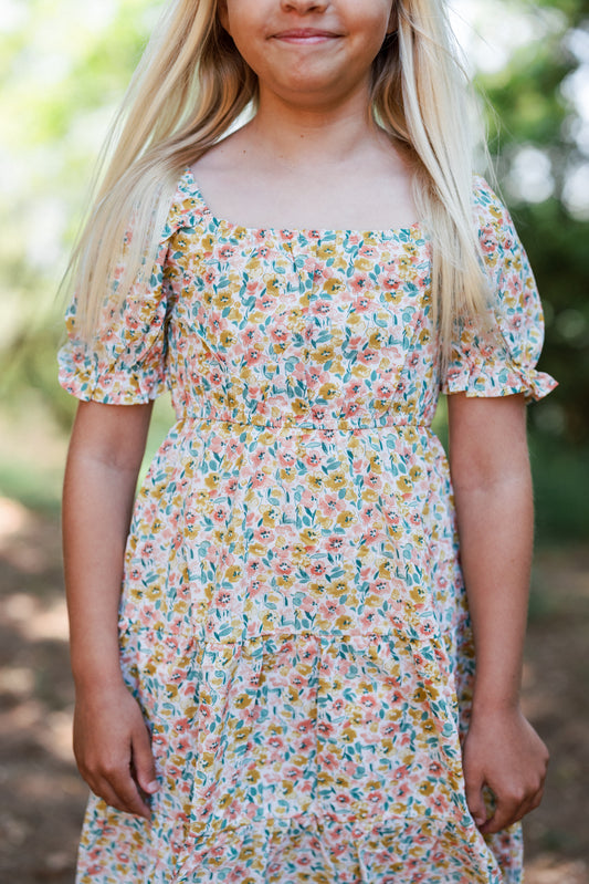 Young girl wearing a floral dress with a blurred natural background