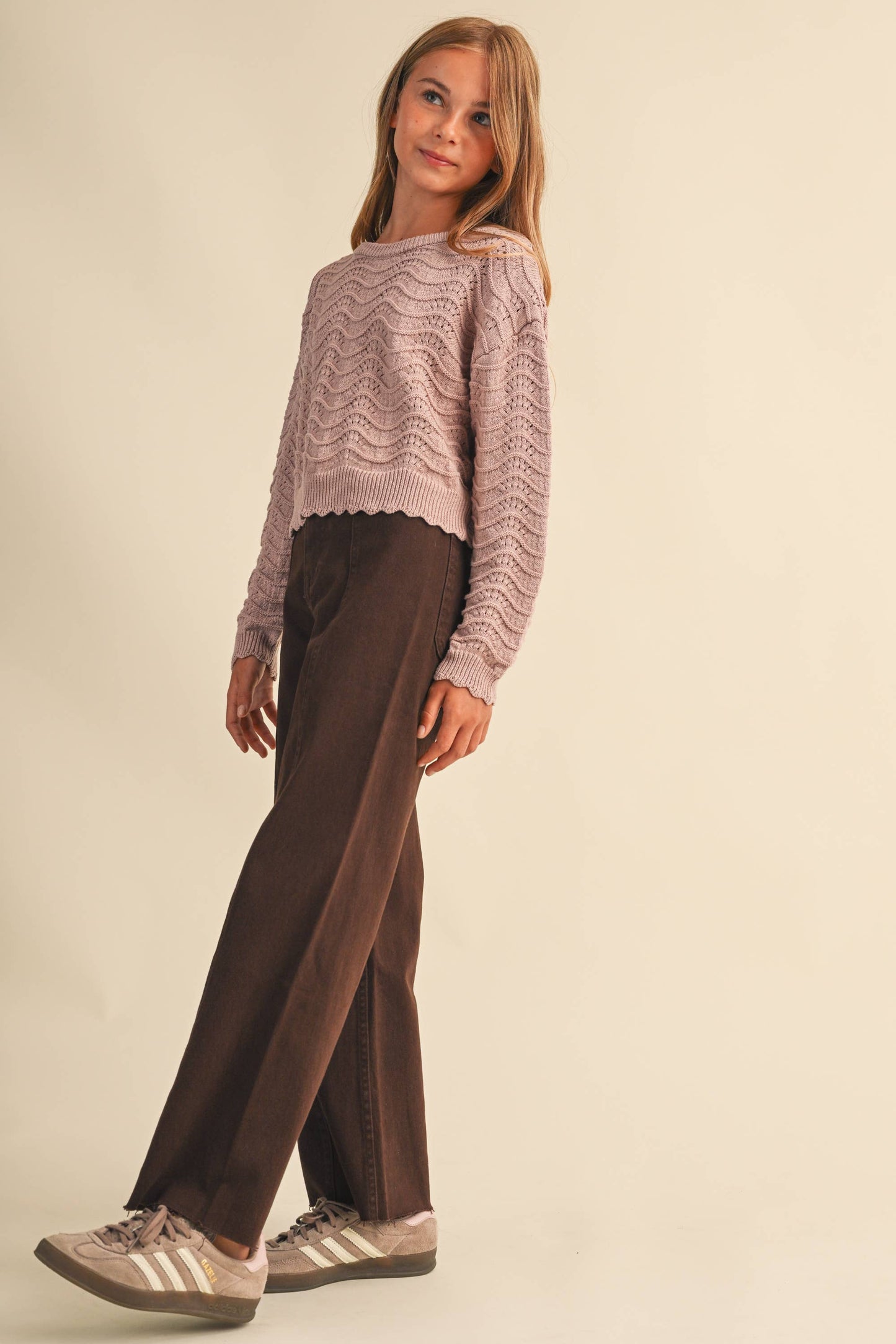 A young girl modeling a mauve colored textured knit sweater