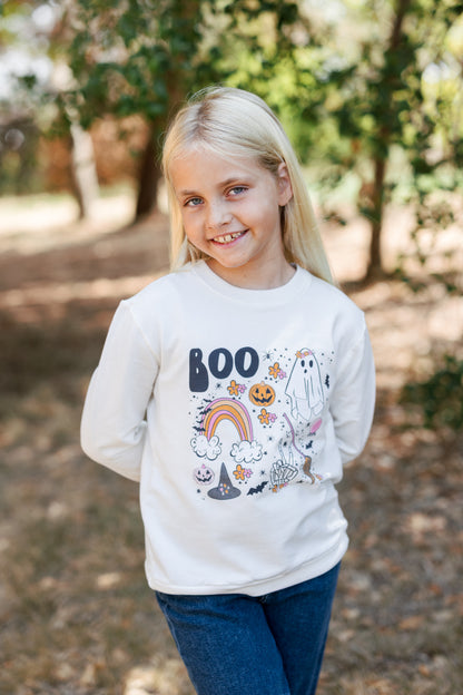 Young girl wearing a white sweatshirt with Halloween-themed graphics outdoors.