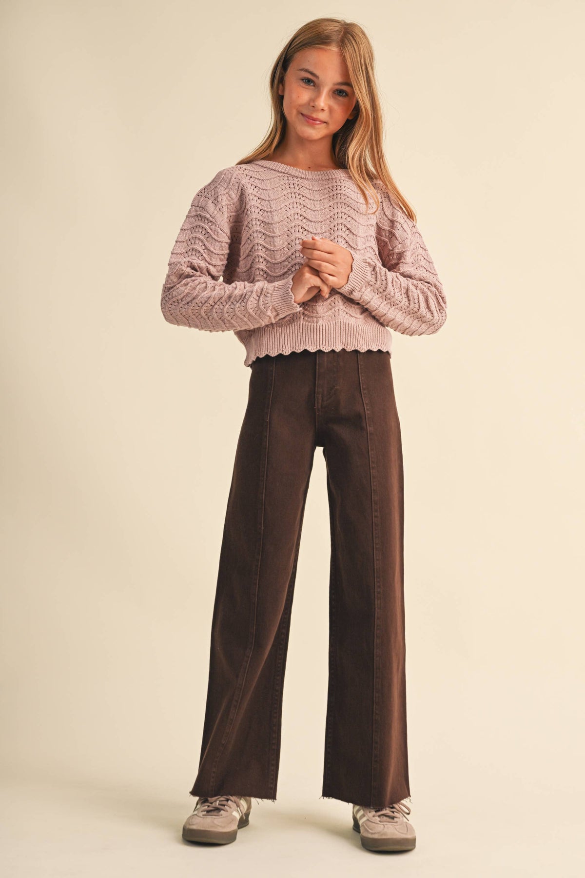 A young girl modeling a dusty pink textured knit sweater